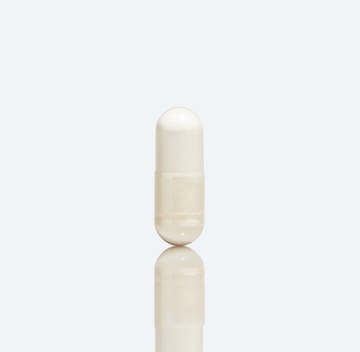 Single Basis capsule standing on a reflective pale blue surface